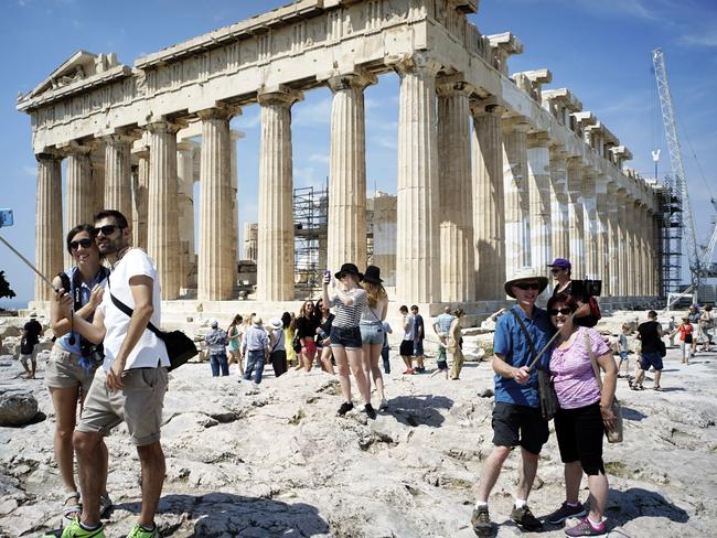 Visitors still coming ... Tourists visit the ancient Acropolis hill, with the ruins of the fifth century BC Parthenon temple. Picture: Milos Bicanski/Getty Images