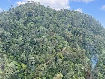 Smoke rising from the thick tree coverage of a mountain range north of Okuloo and Netherdale where it is understood a plane crashed on Saturday, October 28, 2023. Picture: RACQ CQ Rescue