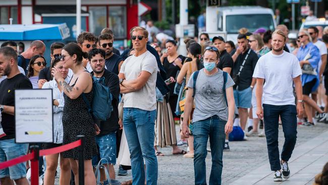 Only one man wears a protective mask as travellers queue up to board a boat at Stranvagen in Stockholm. Picture: AFP.