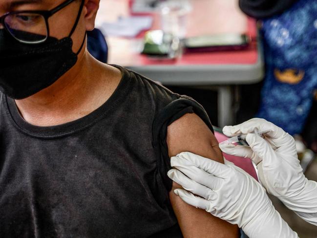 A health worker injects a man with a shot of the Inavac vaccine for Covid-19 at the Jakarta provincial health office on December 19, 2023, during a vaccination campaign held to administer a fifth precautionary vaccine dose amid concerns that Covid-19 cases could spike during the Christmas and New Year holidays. (Photo by BAY ISMOYO / AFP)