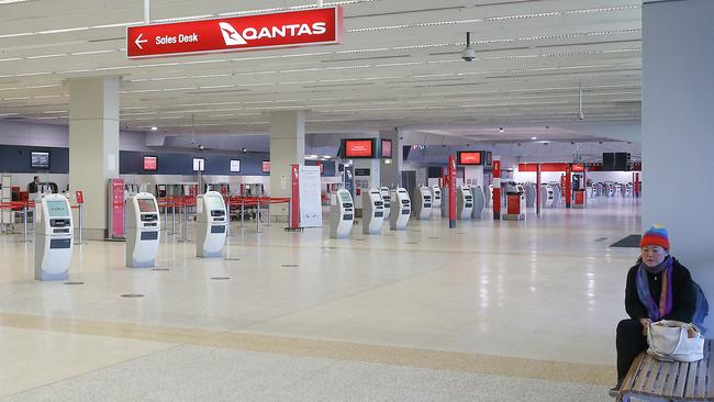 A woman sits alone in the Qantas terminal at Melbourne Airport following border closures between NSW and Victoria. Picture: NCA NewsWire / Ian Currie