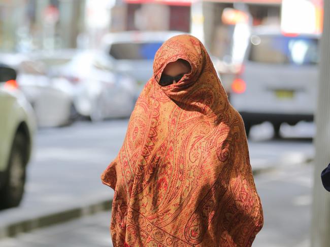 The accused’s partner covered her head with a large orange scarf as she left court. Picture: John Grainger