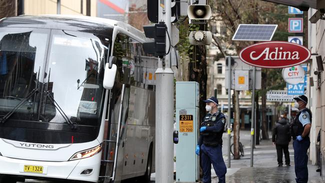 Police outside the Adina Apartment Hotel Sydney as a bus of travellers arrive for their 14-day quarantine. Picture: Jonathan Ng