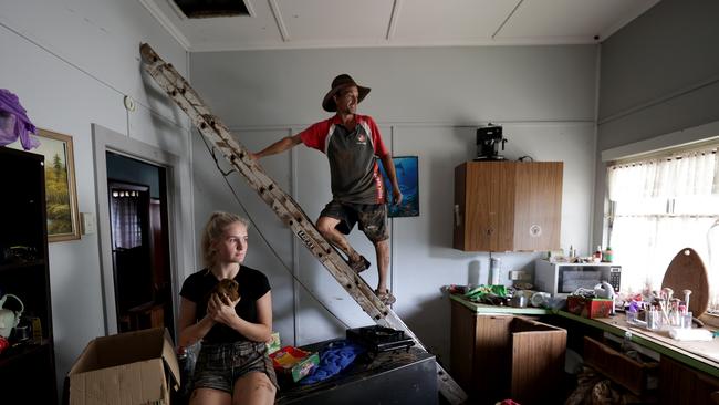 South Lismore resident Andrew Rose lives on Casino St, Lismore and had to punch a wall through the roof to get out and escape rising floodwaters. Andrew and Gemma, 18, are pictured in their kitchen, with Gemma holding a pet guinea pig they saved, on March 4. Picture: Toby Zerna