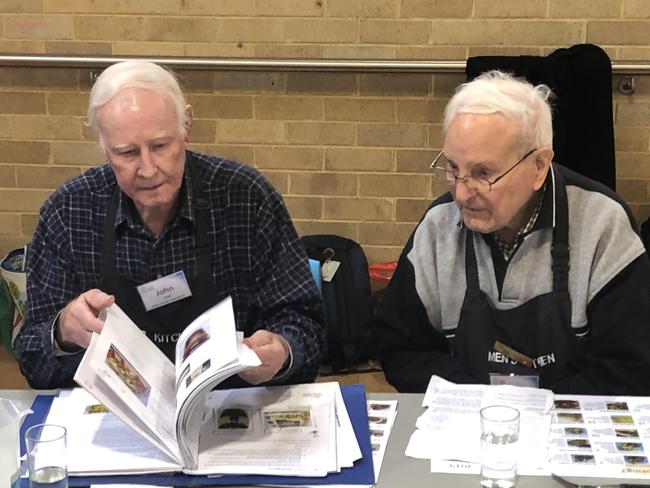 John Coye (left) and Peter Rudland look through a recipe folder during a Men's Kitchen Northern Beaches cooking skills session at the Forestville Community Hall on Friday. Picture: Jim O'Rourke