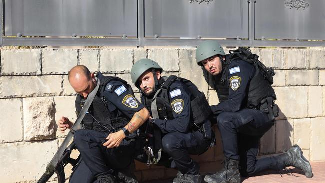 Members of the Israeli forces take cover on the side of a street in Ashkelon. Picture: AFP