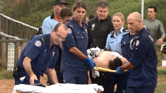 A surfer was comforted by lifeguards and friends after being struck by lightning at Dee Why beach. Picture: TNV Video