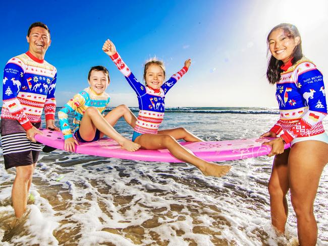 2020 Ugly Xmas Rashie new range.Ethan Whitehead (M, yellow rashie) and Alyssa Tuohy (F) with Brenden Scoffell (M) and Rizu Sawaki (F) holding surf board. Picture: NIGEL HALLETT