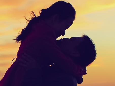 Happy young couple kissing and hugging each other in sunset background