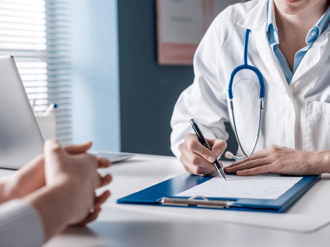 Doctor sitting at desk and writing a prescription for her patient