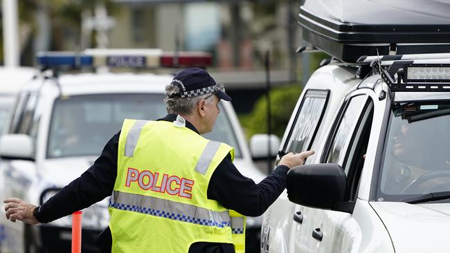 A Queensland police officer speaks with a motorist at a checkpoint at Coolangatta on the Queensland-New South Wales border. (AAP Image/Dave Hunt)