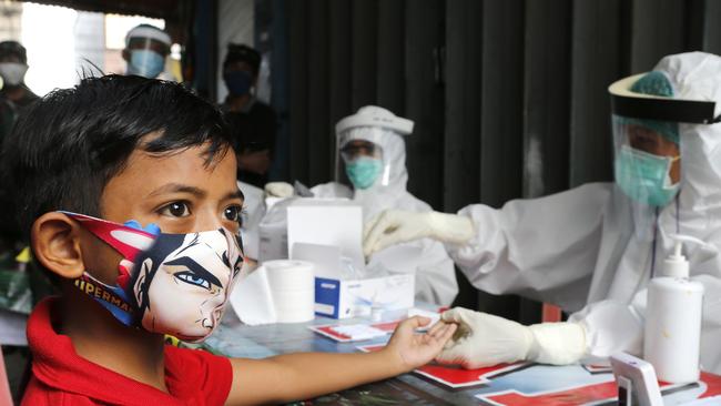 A boy wearing a face mask waits to receive a coronavirus antibody test from health workers at a village in Bali, Indonesia, on Wednesday. Picture: AP