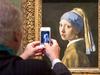 A visitor takes a picture of the "Girl with a Pearl" artwork by painter Johannes Vermeer during a press preview at the renovated Mauritshuis museum in the Hague, the Netherlands, on June 20, 2014. The museum will officially re-open to the public on June 27 after two years of renovations. AFP PHOTO / ANP / LEX VAN LIESHOUT ***Netherlands out*** == RESTRICTED TO EDITORIAL USE, MANDATORY CREDIT OF THE ARTIST, TO ILLUSTRATE THE EVENT AS SPECIFIED IN THE CAPTIONS ==