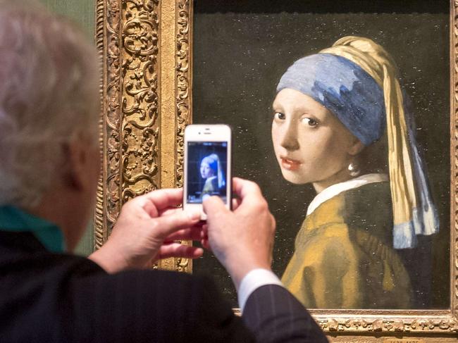 A visitor takes a picture of the "Girl with a Pearl" artwork by painter Johannes Vermeer during a press preview at the renovated Mauritshuis museum in the Hague, the Netherlands, on June 20, 2014. The museum will officially re-open to the public on June 27 after two years of renovations. AFP PHOTO / ANP / LEX VAN LIESHOUT ***Netherlands out*** == RESTRICTED TO EDITORIAL USE, MANDATORY CREDIT OF THE ARTIST, TO ILLUSTRATE THE EVENT AS SPECIFIED IN THE CAPTIONS ==