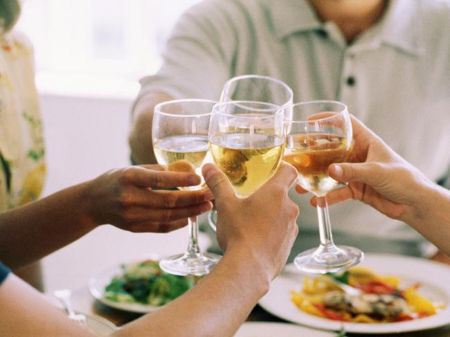 Hands toasting wine glasses at dinner party. Generic image.