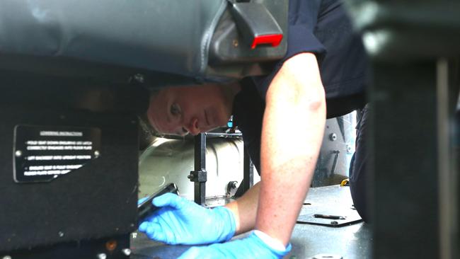 Senior constable Korinne Lardner looks for clues on the floor of a Cairns Taxi vehicle. Picture: Peter Carruthers