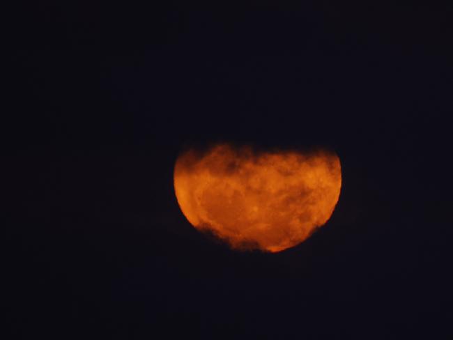 DAILY TELEGRAPH AUGUST 31, 2023. The blue supermoon briefly peaks through the clouds as it rises over Wollongong Harbour. Picture: Jonathan Ng