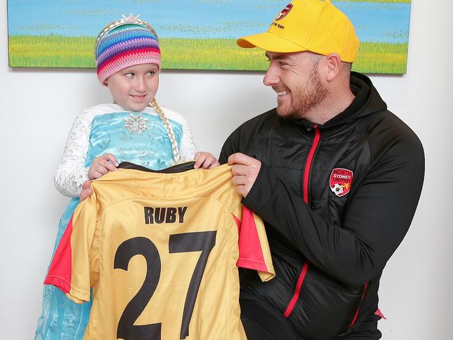 Ruby receives her own football jumper on her fifth birthday from North Sydney United FC head coach Joe Liddle. Picture: Adam Ward