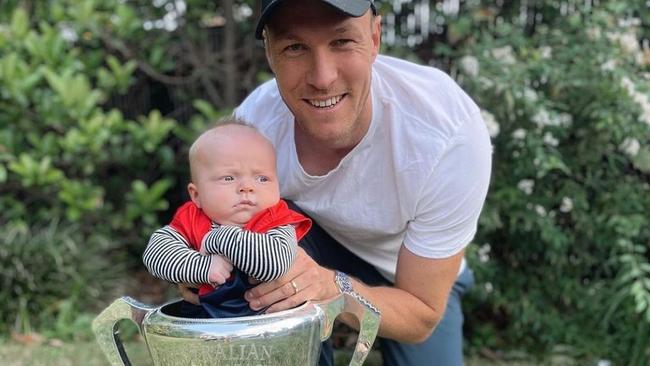 Tom McDonald, with son Leo and last year’s AFL premiership cup, is fighting for his spot in unbeaten Melbourne’s team. Picture: Instagram