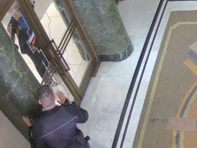 A CCTV image showing Senior Constable Paul Withers interacting with Marcia Mikhael at the Lindt Cafe.