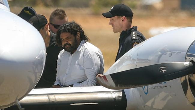 Terence Darrell Kelly boards a plane after being taken into custody by members of the Special Operations Group at Carnarvon airport. Picture: Getty