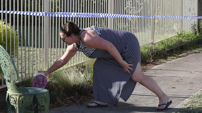 A woman places flowers at the house. Picture: David Crosling