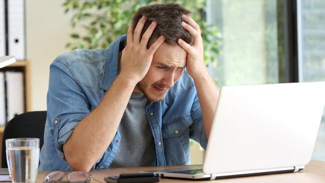 A stressed man at his computer after just realising he has been scammed. Picture: iStock.