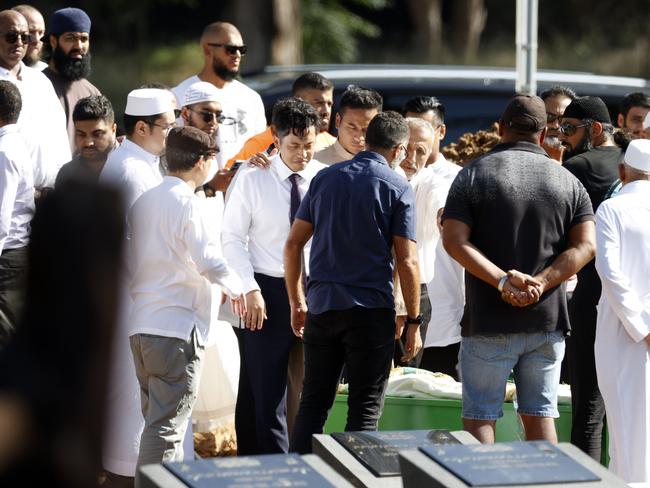 Ian Prahastono comforted at the burial site of his wife. Picture: Jonathan Ng