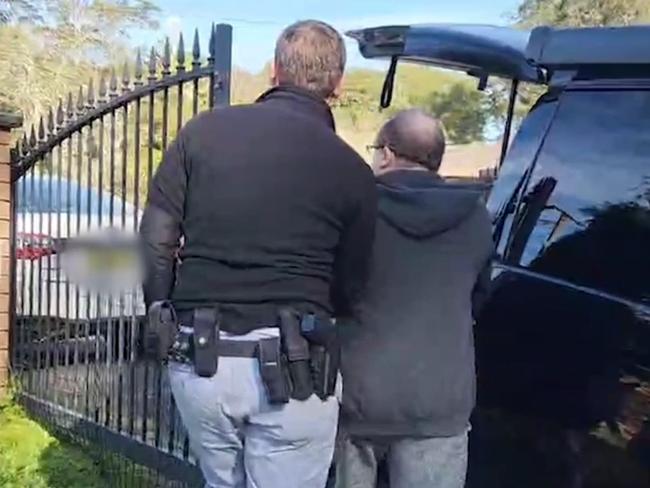 Anthony Michael Ahern (right), of Narara, is arrested by Australian Federal Police officers and charged with possessing terabytes of child abuse material. Picture: AFP