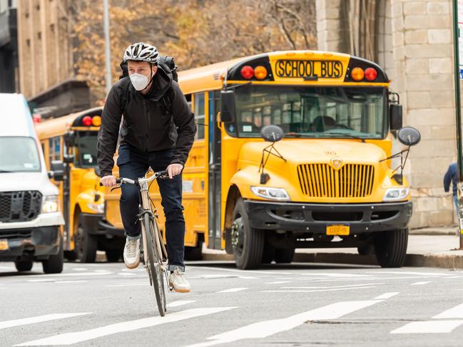 A person rides a bicycle by a school bus in Union Square as New York City continues the re-opening efforts. Picture: Getty Images