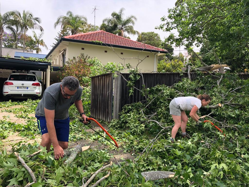 Mark and Natalie Gauci clearing the front of their home in Wareham Crescent, Frenchs Forest, after a violent storm swept through. Picture: Jim O'Rourke.