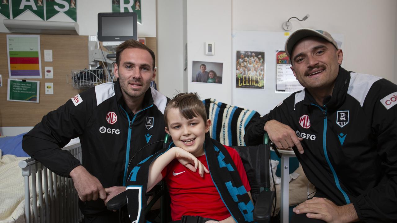 Sam Powell-Pepper and Jeremy Finlayson are surprising Port supporter Fraser Suggate, 9, to lift his spirits as he battles brain cancer in the WCH ahead of the team's clash against Sydney. Picture: Brett Hartwig