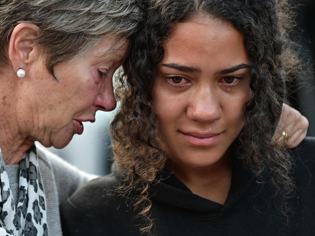 Mourners cry after leaving flowers in tribute to victims in Christchurch.