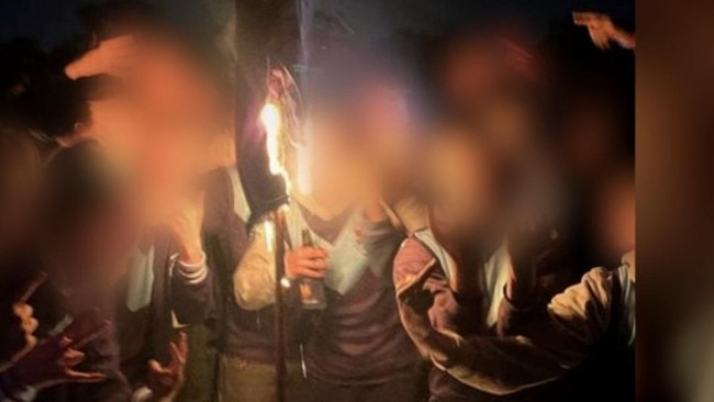 7NEWS has obtained images of students posed for pictures as a rival college's sports jacket was set on fire. Picture: 7NEWS