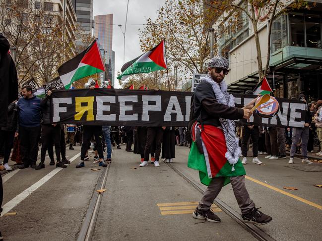 A protester plays the drum with a sticker of Israel crossed out. Picture: Tamati Smith