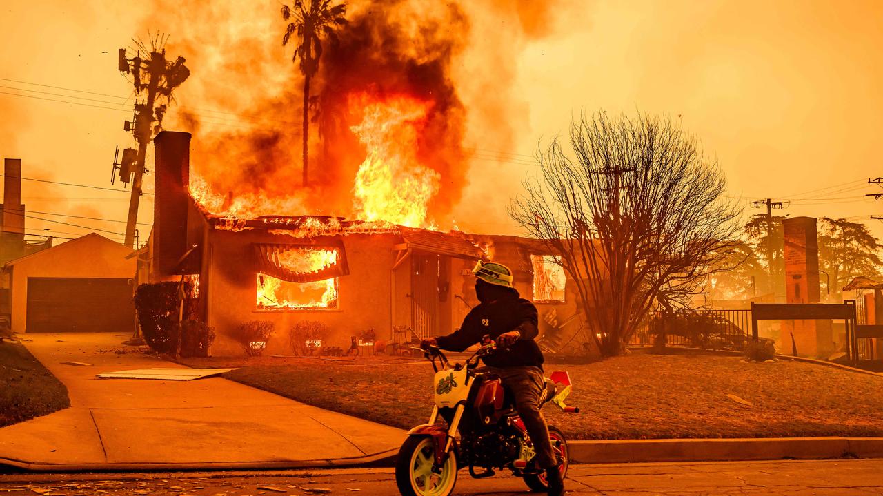 A motorcyclist stops to look at a burning home during the Eaton fire in the Altadena area of Los Angeles county, California. Photo by JOSH EDELSON / AFP