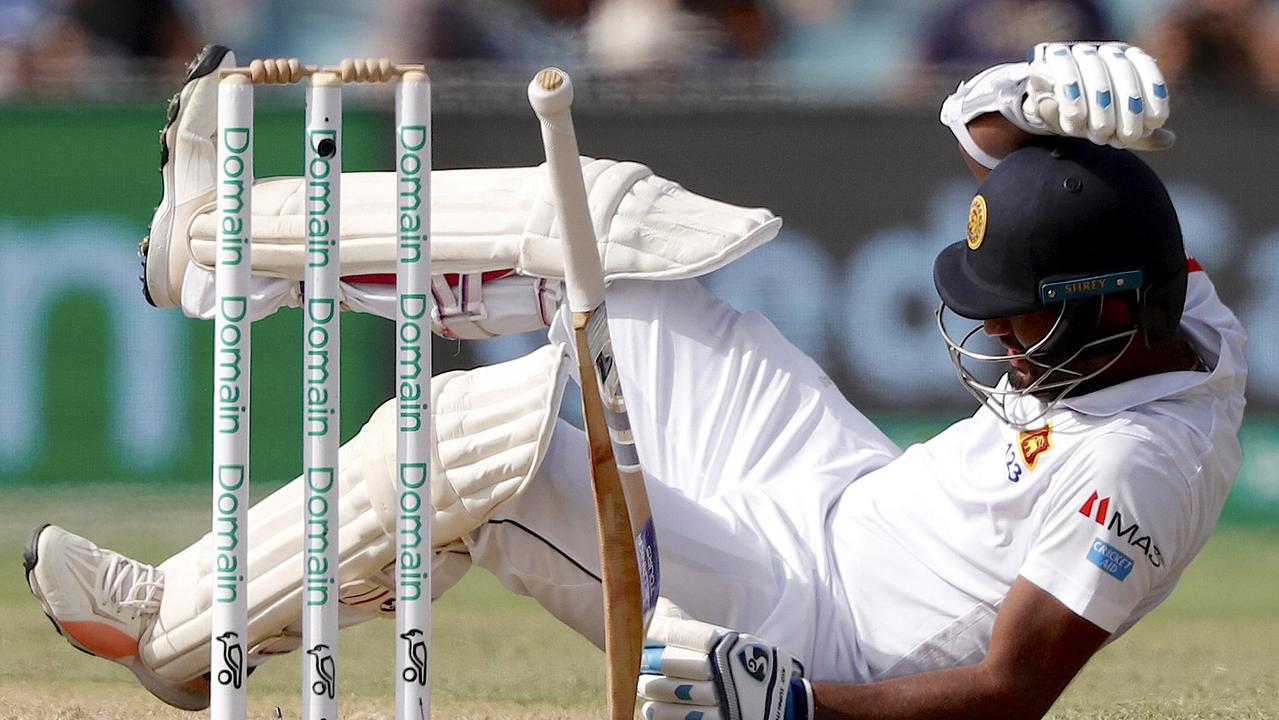 Sri Lanka's Dimuth Karunaratne falls to the ground after being struck by a delivery by Australia's Pat Cummins.