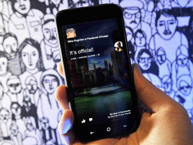 A Facebook employee displays an HTC phone with the new Home operating system against the backdrop of a decorated wall at Facebook's Headquarters office in Menlo Park, California on April 04, 2013. Facebook on Thursday unveiled a software suite which stakes out a "home" on Android smartphones as it steps up its challenge to Apple and Google in the booming mobile market. Facebook called the new software "a new way to turn your Android phone into a great, living, social phone." The software, which allows users to see Facebook's "Cover Feed" when they turn on their phones, will be available for download from Google's online Play shop in the United States starting April 12, Zuckerberg said. AFP PHOTO / Josh EDELSON