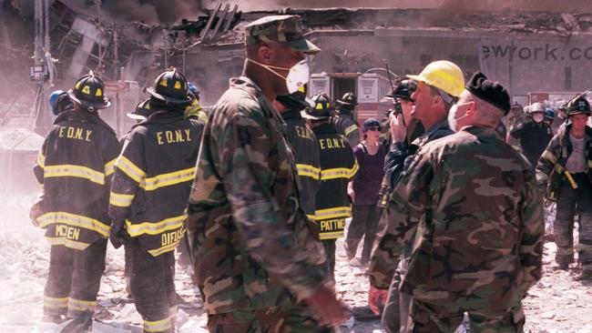 New York City firefighters and military personnel stand near Ground Zero.