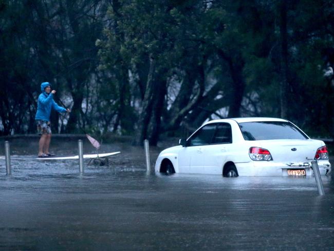 A person on a paddle board on flooded Goodwin St, near Narrabeen Lagoon, after heavy rain in February, 2020. Picture: Damian Shaw