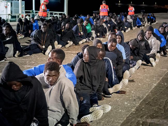 Part of a group of 496 migrants sit on the pier following their arrival at the Port of Granadilla in Tenerife, Spain. Picture: Desiree Martin/AFP