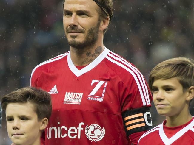 David Beckham, upper left, stands with his children Cruz, left, Harper, bottom, and Romeo before the Unicef Match for Children charity football match between a Great Britain and Ireland team and a Rest of the World team at Old Trafford Stadium, Manchester, England, Saturday, Nov. 14, 2015. (AP Photo/Jon Super)