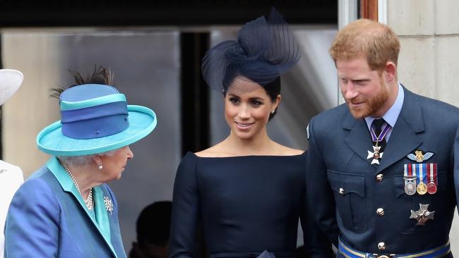 Queen Elizabeth, Meghan, Duchess of Sussex, and Prince Harry, Duke of Sussex watch the RAF flypast on the balcony of Buckingham Palace in 2018 in London.