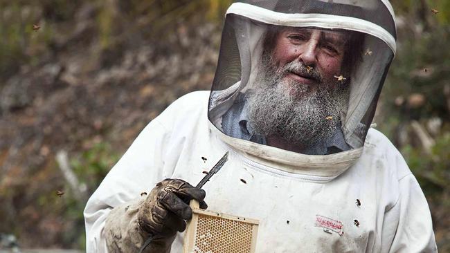 Beekeeper Bruce Direen with a frame and smoker at hives lined along a road near the Picton River near Geeveston. Supplied for Elaine Reeves taste colum. Picture; PAUL COUNTRY