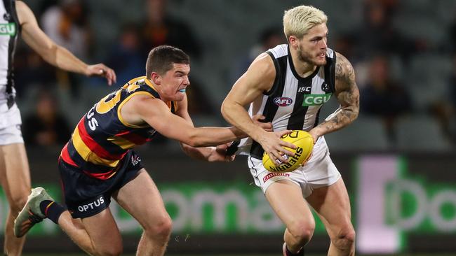 Jack Crisp attempts to charge through a tackle from Adelaide’s Ned McHenry.