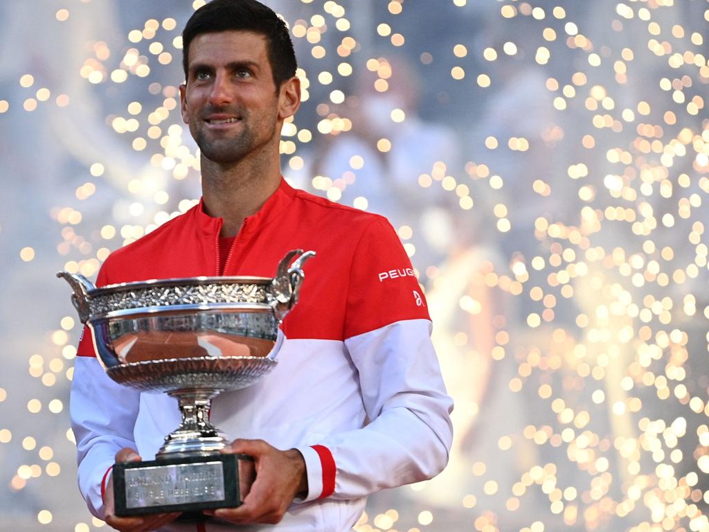 Novak Djokovic poses with the Mousquetaires Cup (and a lot of sparks in the background) after winning the 2021 French Open final for his second Roland Garros title. Picture: Anne-Christine Poujoulat/AFP