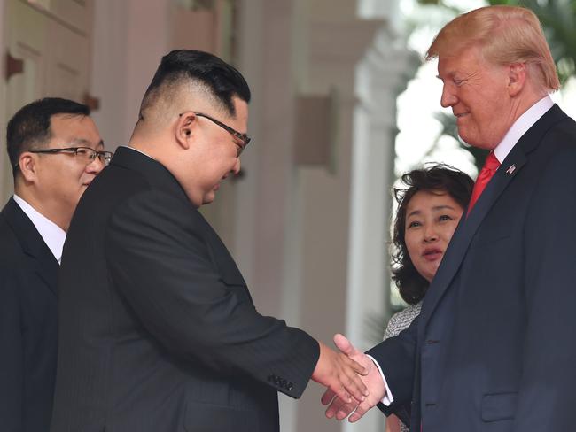 Donald Trump shakes hands with Kim Jong Un as they meet at the start of their historic US-North Korea summit, with both intrepreters by their sides. Picture: AFP