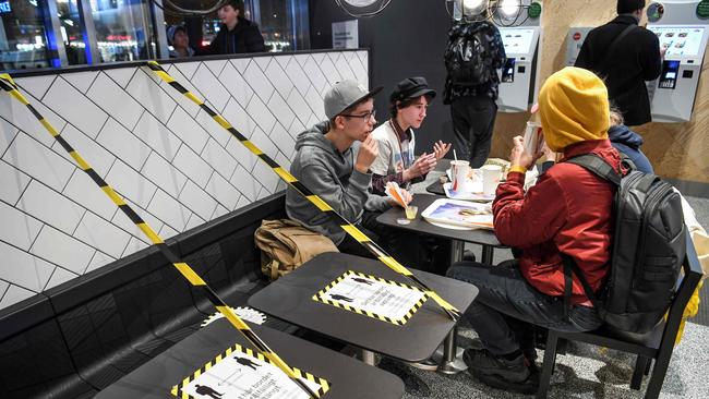 Guests enjoy their meal at a fast food restaurant next to taped off tables in central Stockholm. Picture: AFP