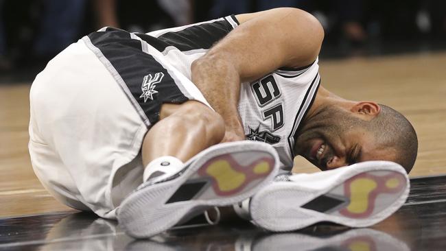 San Antonio Spurs' Tony Parker holds his left leg after getting injured against the Rockets.