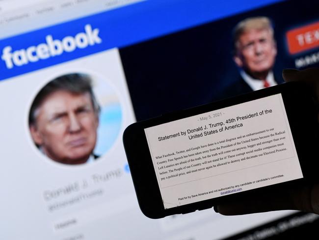 In this photo illustration, a phone screen displays the statement of former US President Donald Trump on his Facebook page background, on May 5, 2021, in Arlington, Virginia. - Donald Trump said May 5, 2021 it was a "total disgrace" for online giants to institute social media bans, after a Facebook board upheld the company's restriction against the former US president which he argued infringed on his free speech."What Facebook, Twitter, and Google have done is a total disgrace and an embarrassment to our country," Trump said in a statement. (Photo by Olivier DOULIERY / AFP)